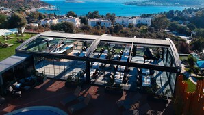 A rooftop terrace with outdoor seating and a glass enclosure overlooking a coastal cityscape. - Roas Hotel (Bodrum)