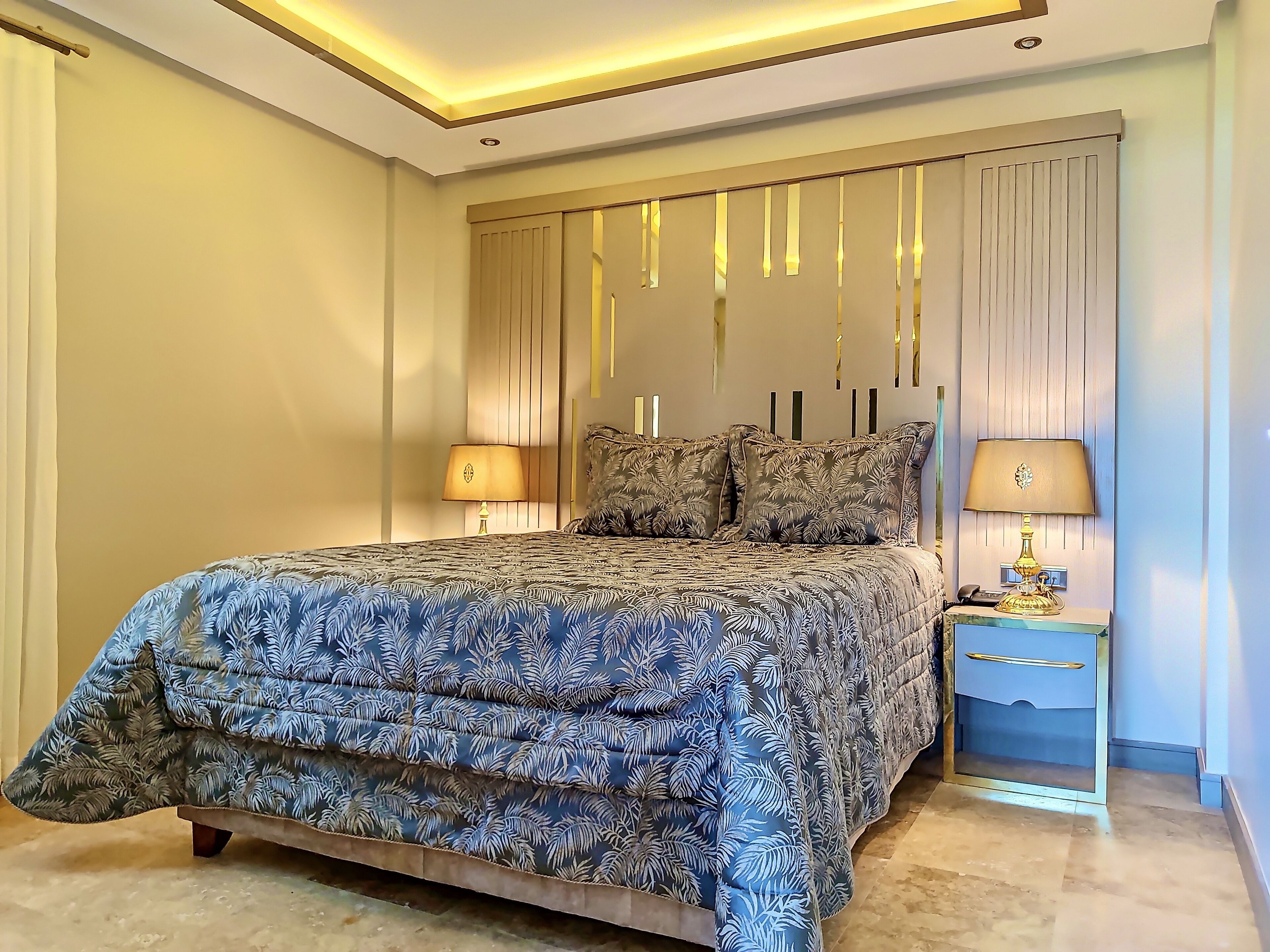 A bedroom with a large bed, two bedside tables, and a nightstand with a lamp.
