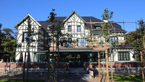 A large, two-story building with a symmetrical facade, a covered entrance, and a brick base. - Hotel Porta Cite (Maasmechelen)