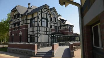 Un edifici d'estil Tudor amb façana de maó, diverses finestres i una zona d'estar exterior coberta.