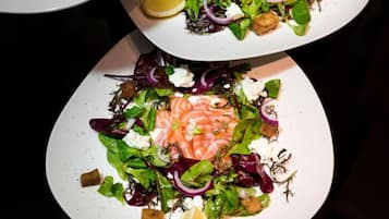 Un plato de comida con salmón, vegetales verdes y crutones.