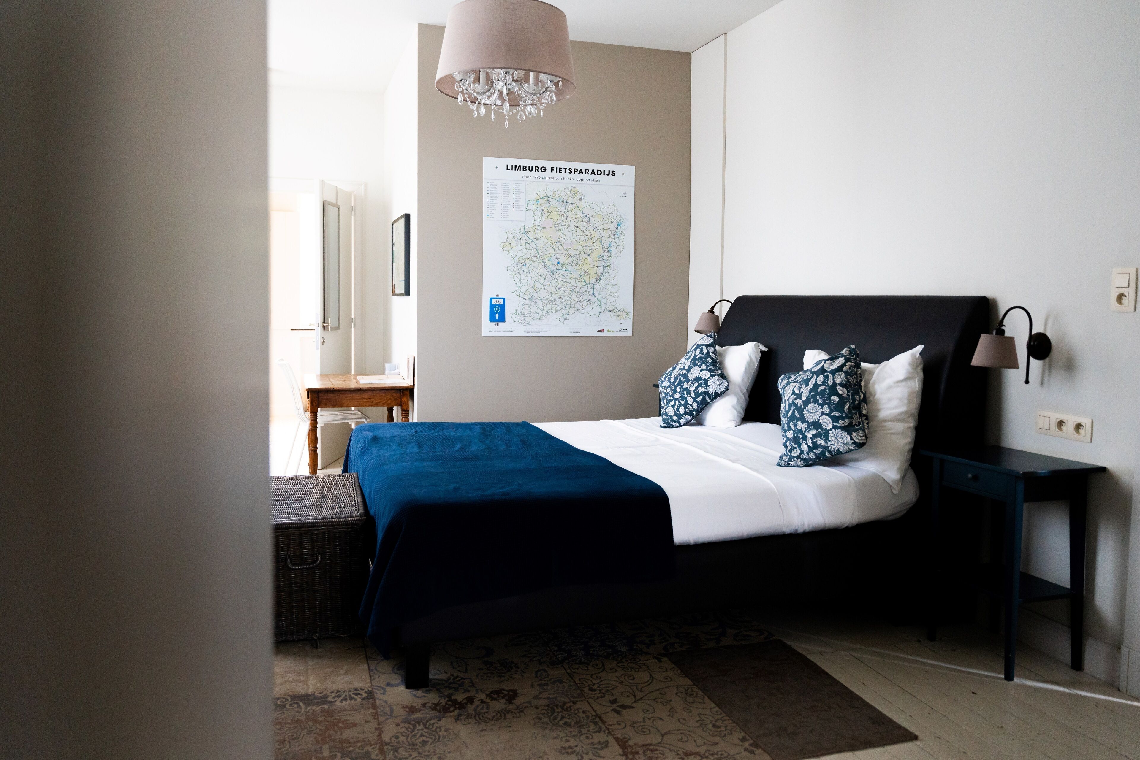 A bedroom with a bed, a map on the wall, a lamp, and a nightstand.