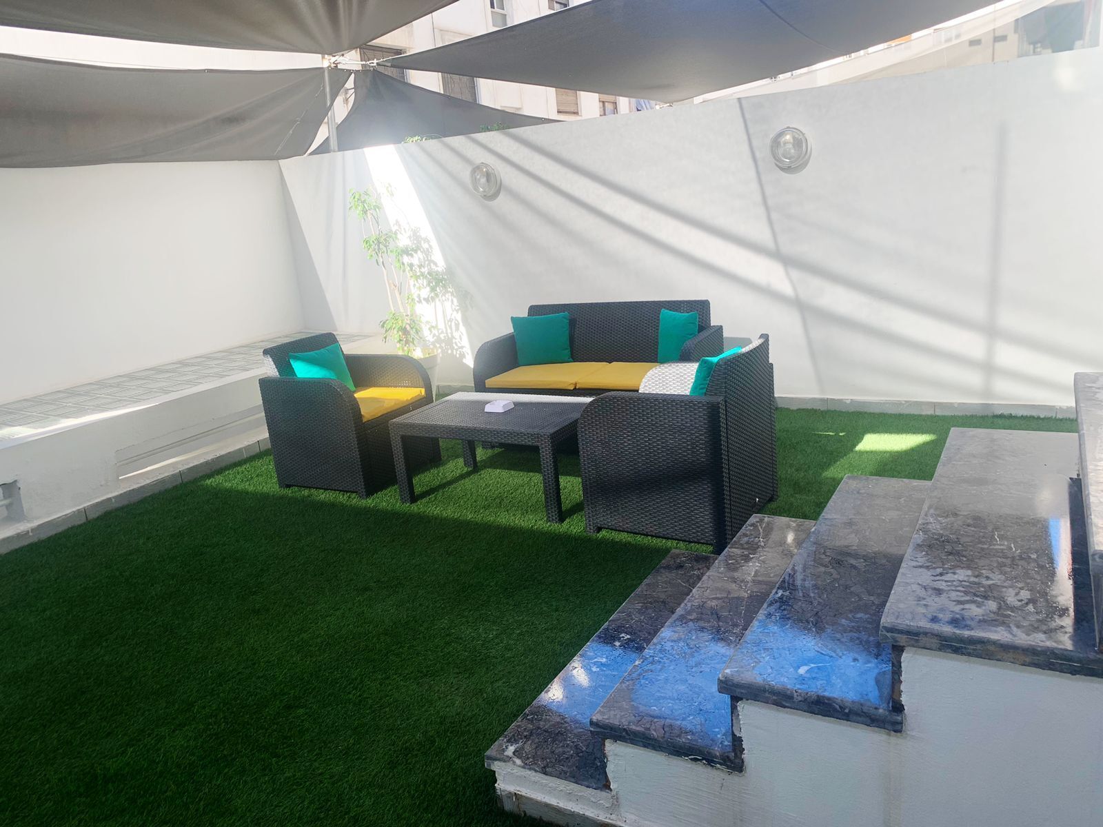 A patio area with outdoor furniture, artificial grass, and a water feature.