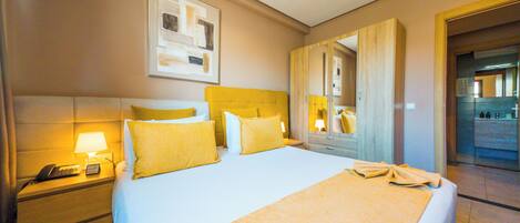 A hotel room with a large bed, a bedside table with a lamp, a phone, and a mirror.