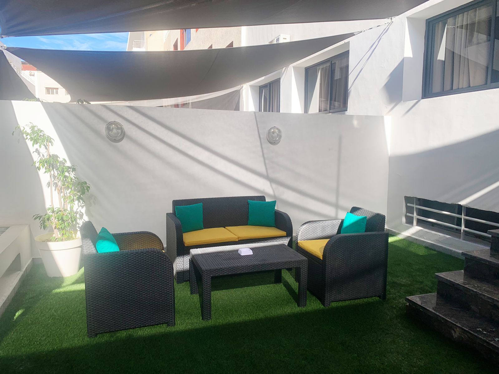 A patio area with a sofa set, a small table, and a potted plant.