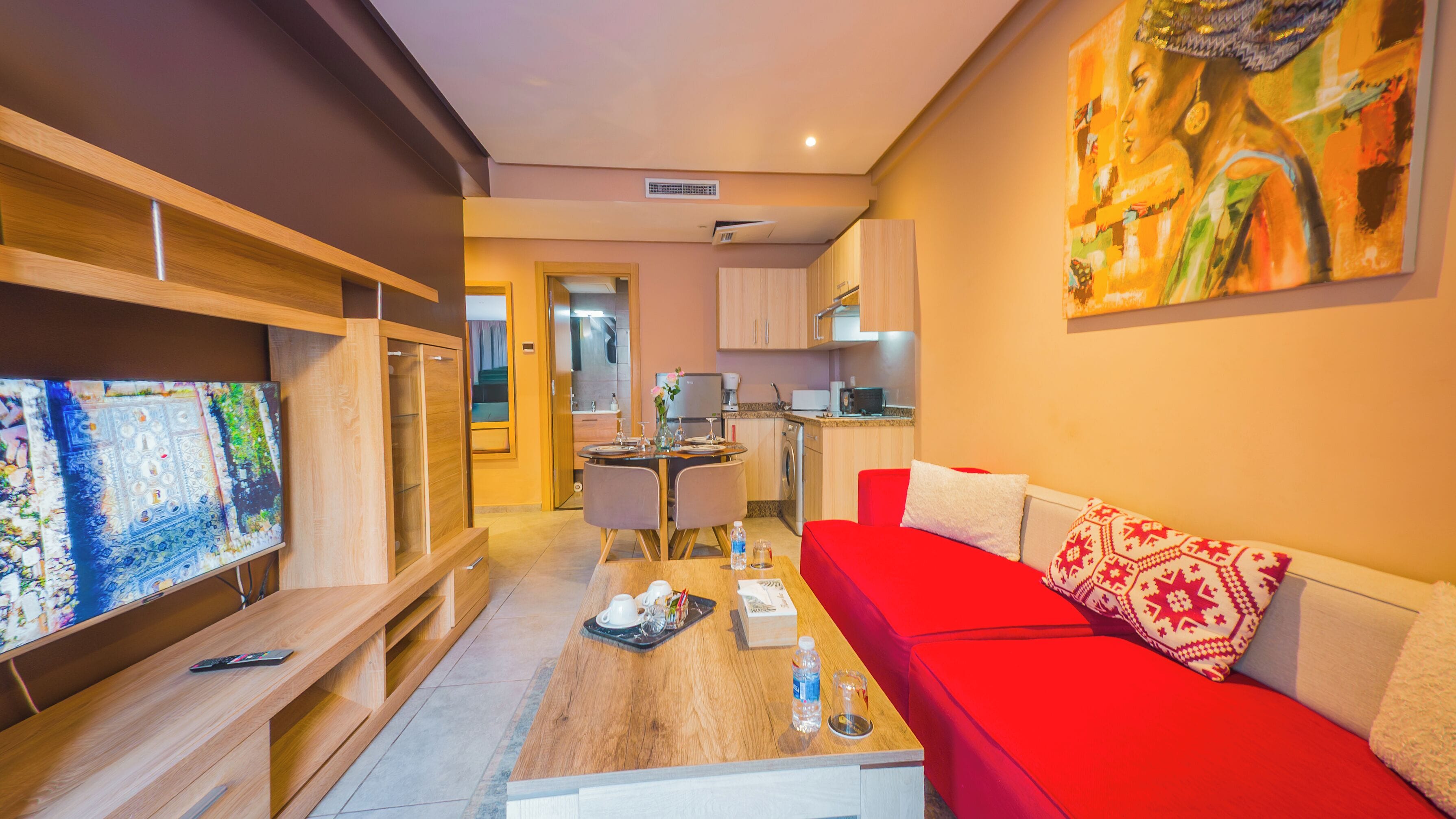 A compact living space with a red sofa, a dining area, and a kitchen.