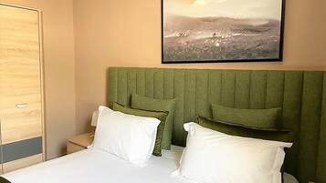 Une chambre d’hôtel avec un lit, deux oreillers, une table de chevet et un tableau encadré au mur.