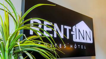 A sign for RENT-INN Suites Hotel with a modern design.