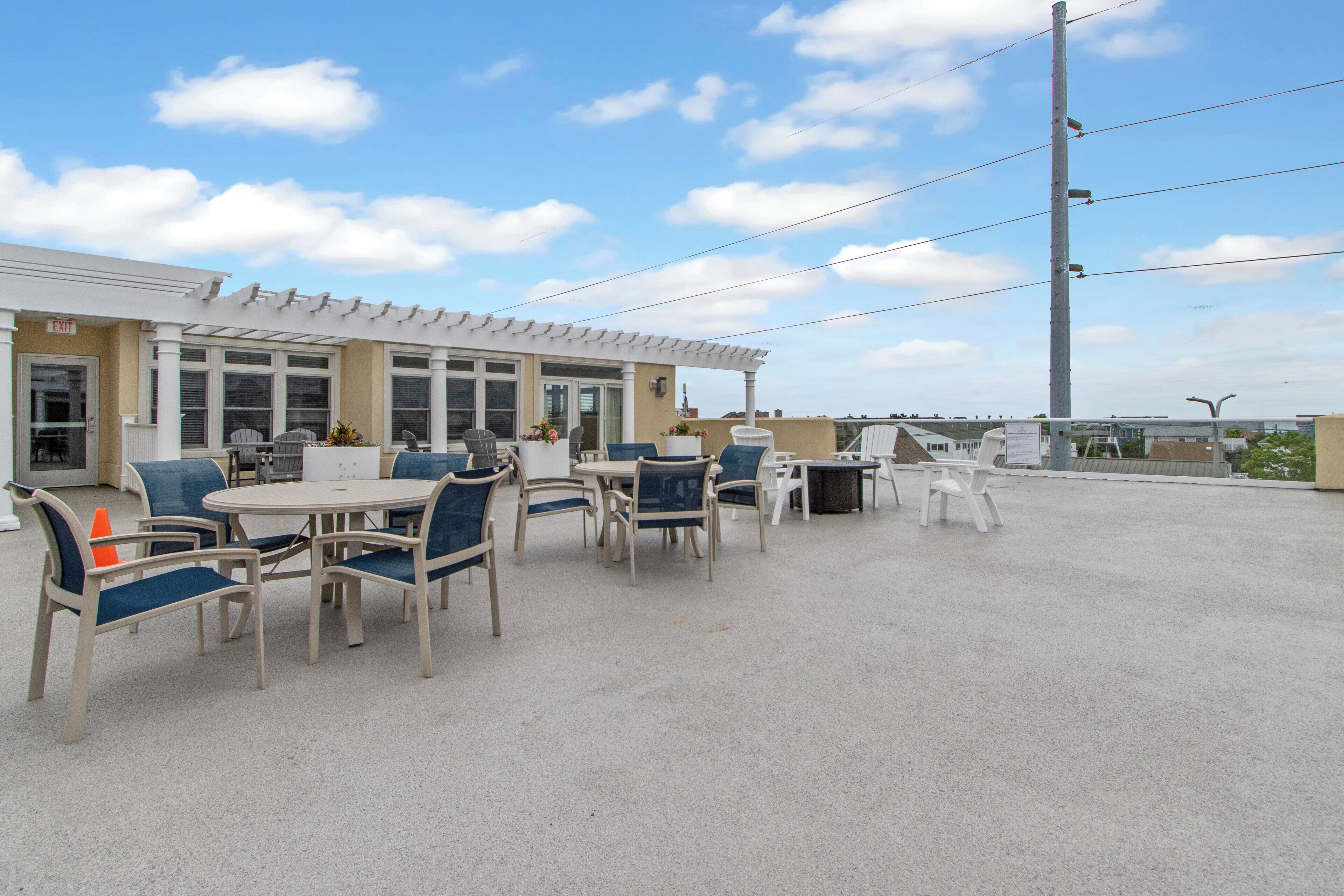 An outdoor patio area with multiple tables and chairs, a covered seating area, and a building with an 'EXIT' sign.