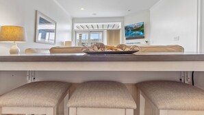 Une cuisine moderne dotée d’un îlot central, d’un coin repas avec un canapé et d’un téléviseur fixé au mur.