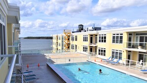 Un espace piscine avec vue sur l’eau, des chaises longues et un poste de surveillance pour les sauveteurs.