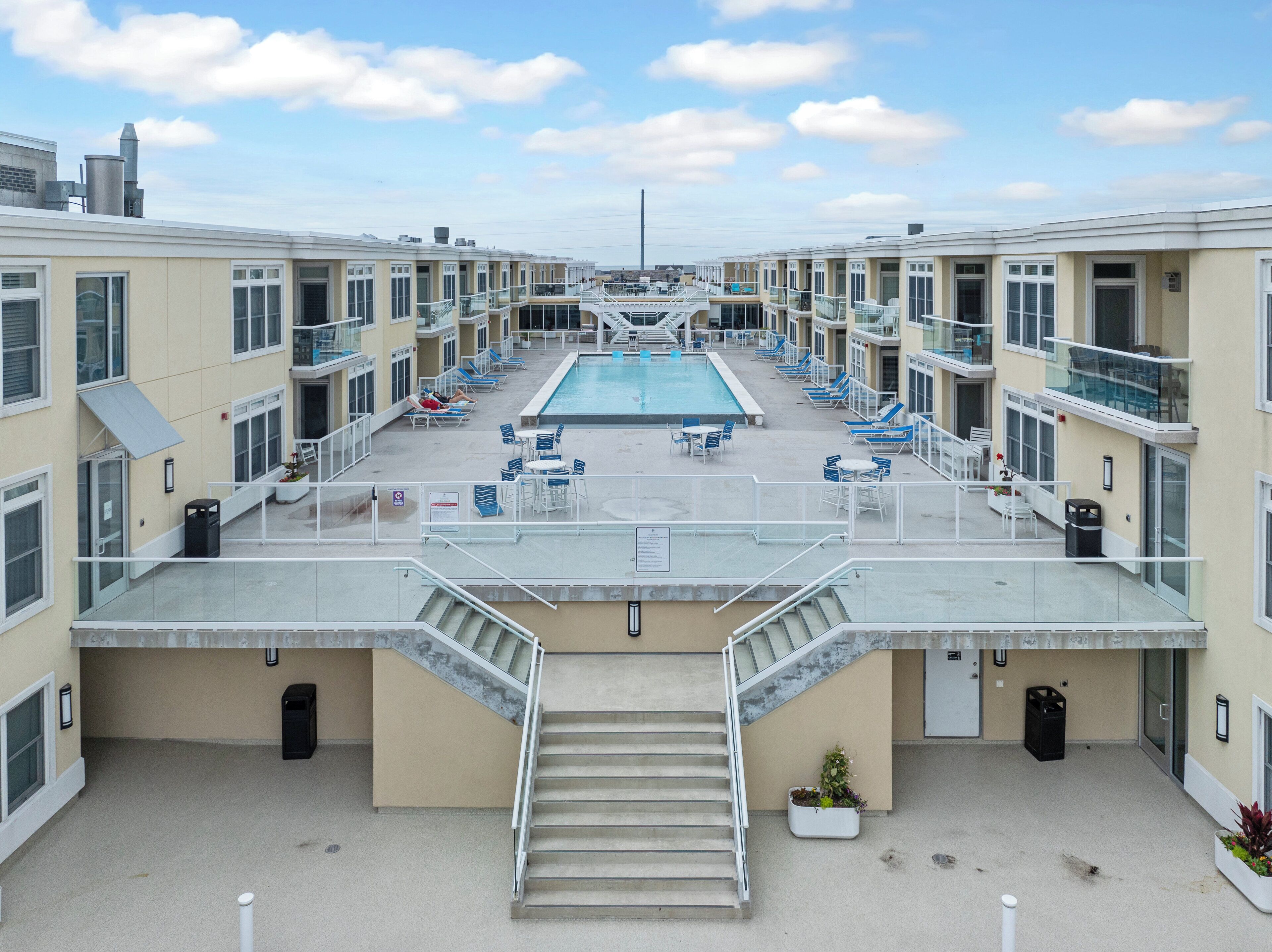 Un espace piscine aménagé sur le toit, comprenant plusieurs chaises longues et une piscine centrale.