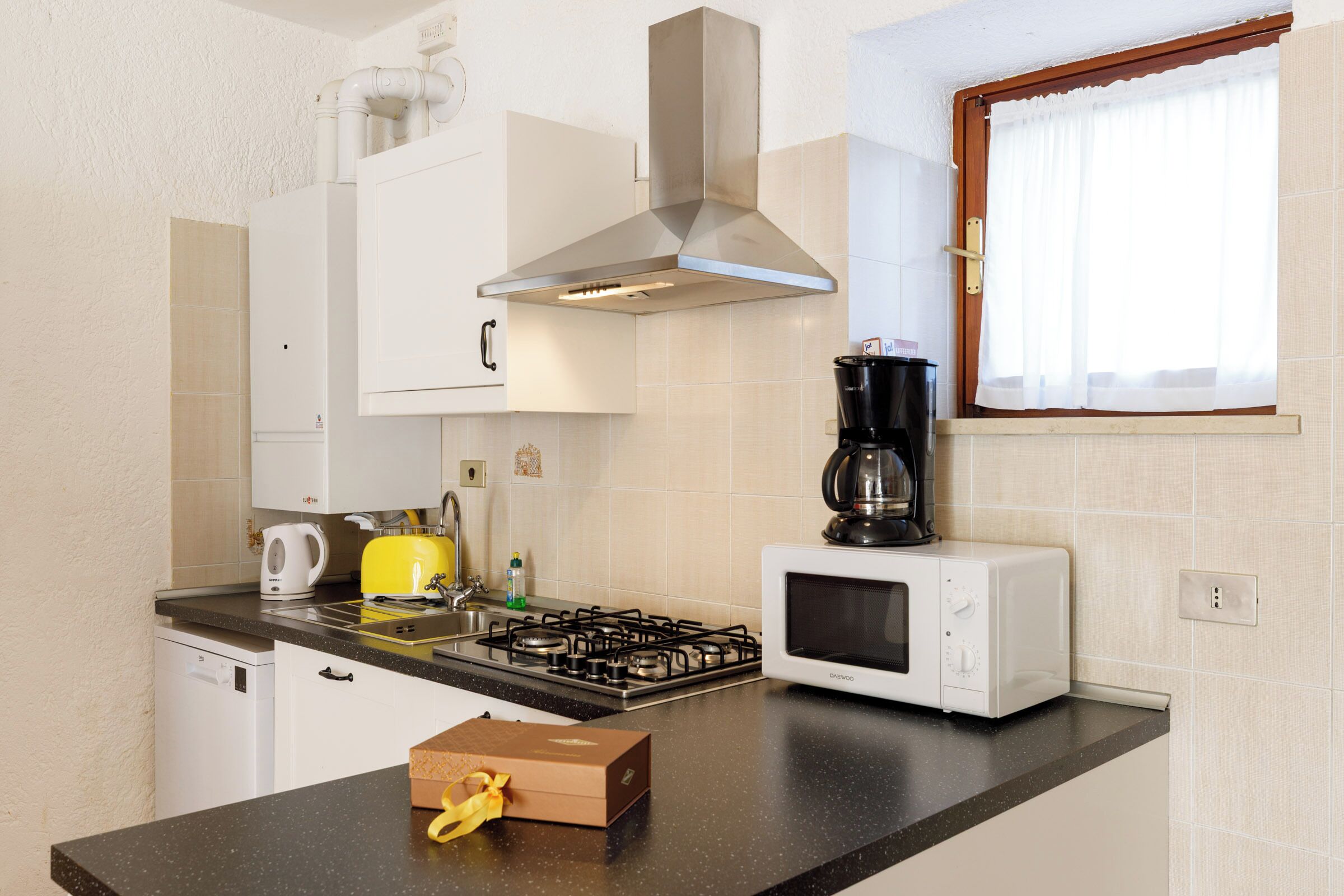 A kitchen with a gas stove, a microwave, a coffee maker, and a toaster.
