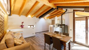 Une cuisine moderne avec des poutres en bois, un coin repas avec une table et des chaises en bois, et un espace de vie chaleureux avec un canapé.