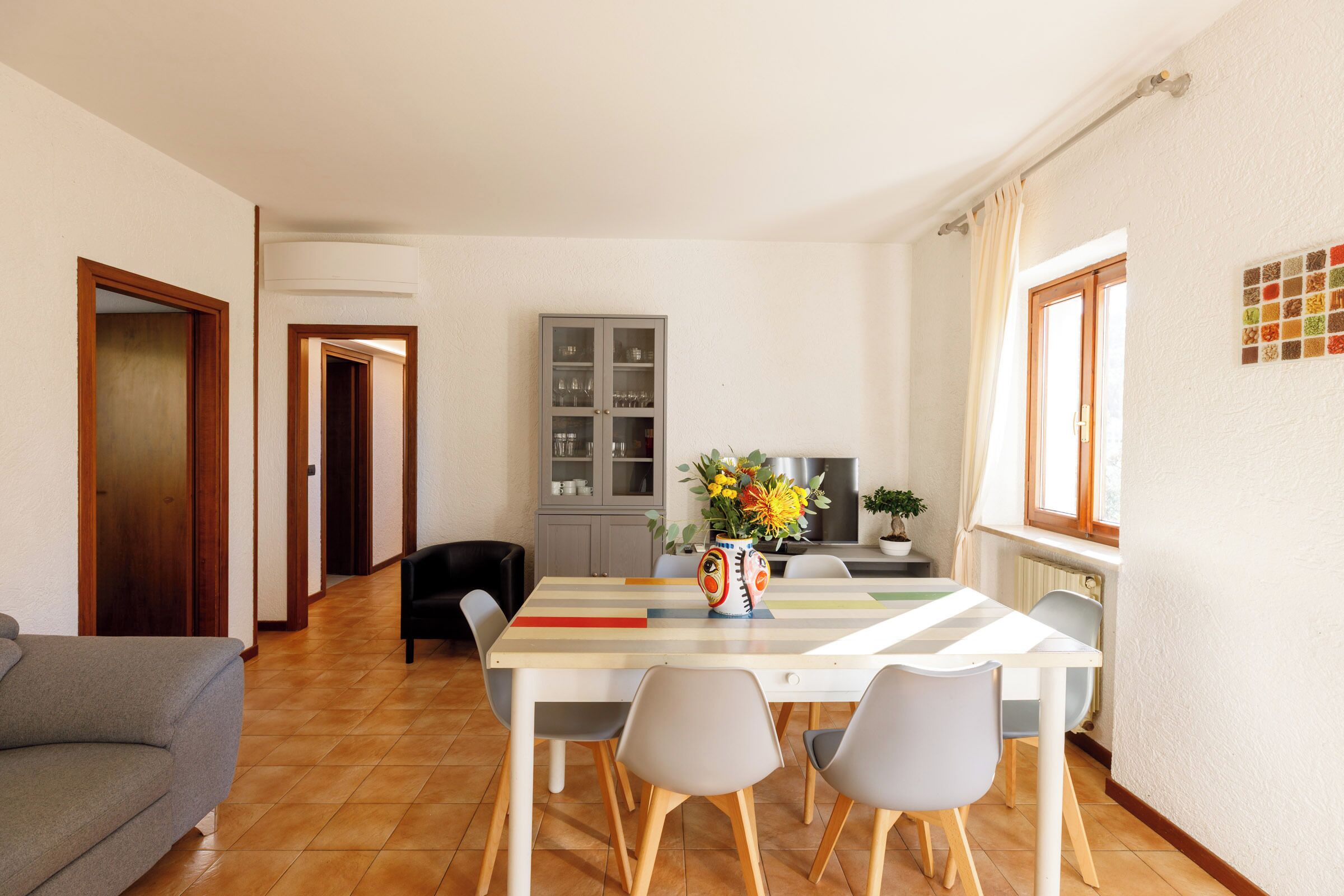 A dining area with a striped table, chairs, and a cabinet with glass doors.