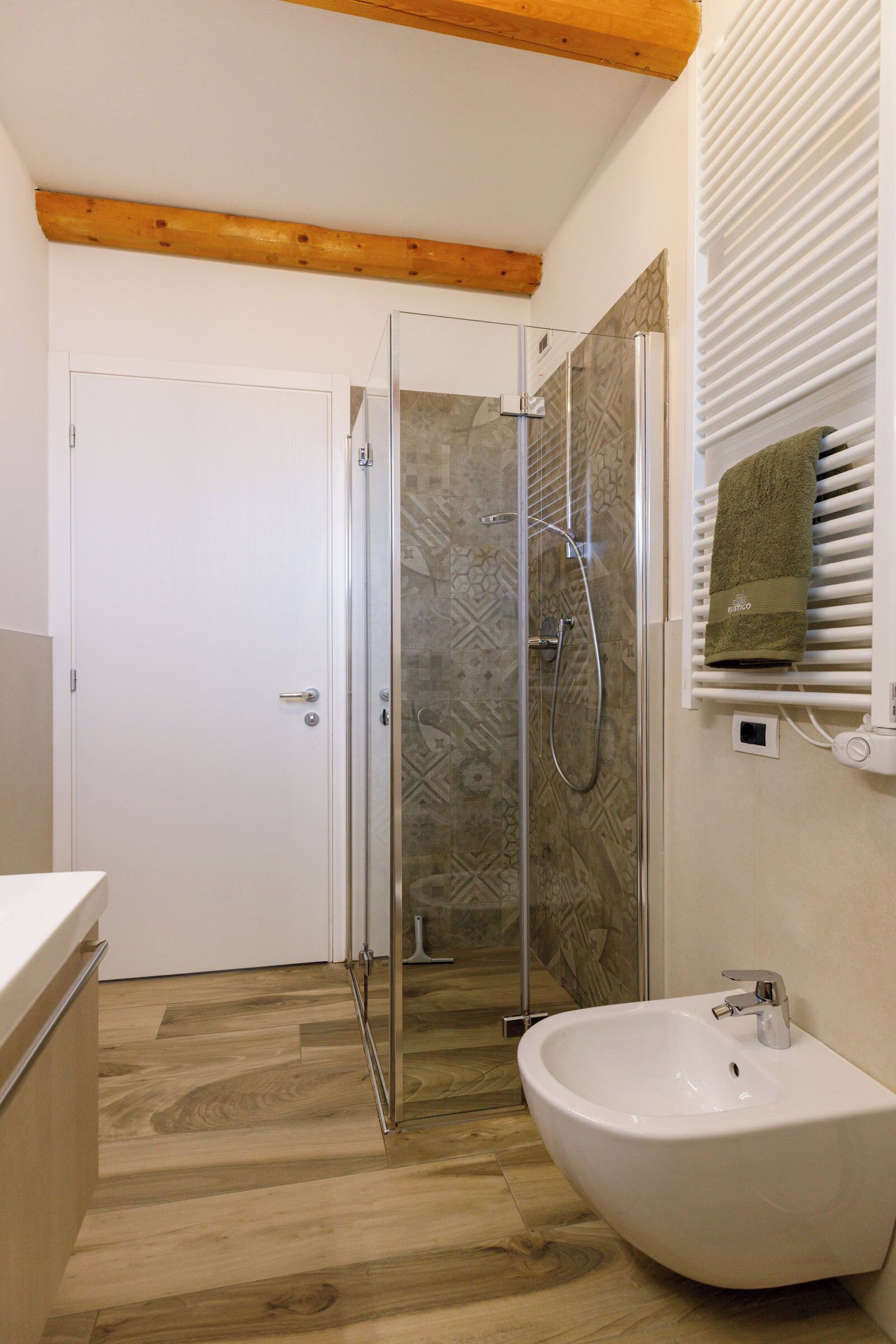 A bathroom with a glass-enclosed shower, a white sink, and a towel rack with a towel.