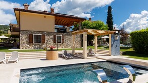 Un espace piscine agrémenté d’un bâtiment en pierre, de chaises longues et d’une pergola.