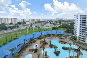 A resort with multiple swimming pools, palm trees, and a view of the cityscape. - Beautiful, Updated 11th Floor Full Two Bedroom Condo at The Palms of Destin! (Destin)