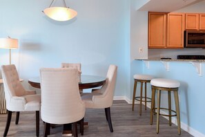 A dining area with a round table and four chairs, a bar stool, and a pendant light. - Gorgeous 12th Floor Views at The Palms of Destin! (Destin)