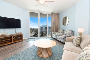 A modern living room with a flat-screen TV, a round coffee table, a sofa, and a balcony with a view.