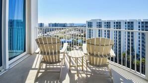 A balcony with two Adirondack chairs and a small table, overlooking a cityscape with high-rise buildings and a clear sky. - Gorgeous 12th Floor Views at The Palms of Destin! (Destin)