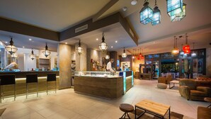 Un espace bar moderne doté d’un comptoir central, de tabourets de bar et de luminaires suspendus.