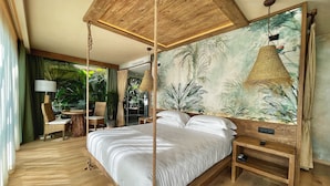 Une chambre spacieuse dotée d’un lit à baldaquin, d’une grande fresque représentant une végétation tropicale et d’un plancher en bois.