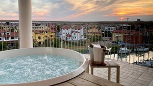Un jacuzzi sur un balcon avec vue sur une marina et des immeubles.