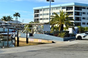 A marina with boats docked, a sign indicating no triple axle trailers, and a building with balconies.