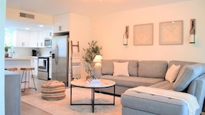 A modern kitchen with white cabinets, a stainless steel refrigerator, and a dining area with stools. - Newly renovated coastal home; Marina, Pools, Lagoon, Bikes, Tiki’s and More! (Key Largo)