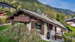 A chalet-style building with a stone facade, wooden balcony, and a stone roof.