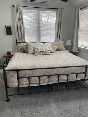 Relax in a serene bedroom with a large bed and plush pillows, featuring a bedside table and lamp.