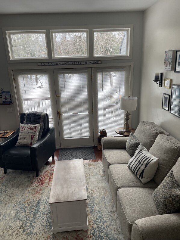 Relax in this cozy space with a comfortable armchair, sofa, and wall-mounted lamp.