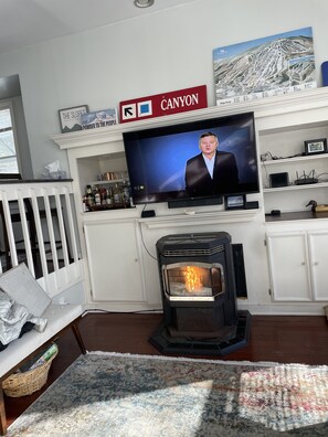 Cozy living room with a TV, wood-burning stove, and crib.