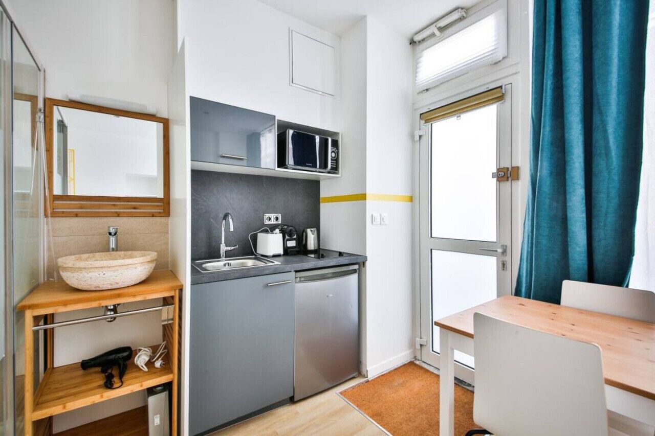 Une cuisine compacte équipée d’un évier, d’un four à micro-ondes et d’un petit plan de travail.