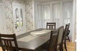 A dining area with a rectangular table, six chairs, and a floral wallpapered wall.