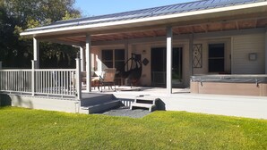 A covered outdoor area with a patio, seating, and a hot tub. - Beautiful house located 5 minutes drive to EAA AIRVENTUE (Oshkosh)