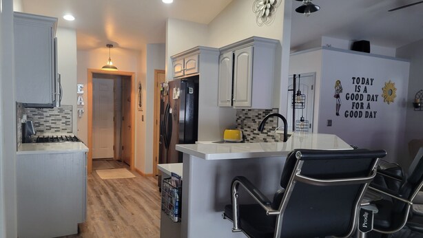 A modern kitchen with a central island, bar stools, and a decorative wall with a motivational quote. - Beautiful house located 5 minutes drive to EAA AIRVENTUE (Oshkosh)