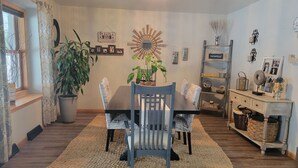 A dining area with a wooden table, two chairs, a large potted plant, and a decorative wall hanging. - Beautiful house located 5 minutes drive to EAA AIRVENTUE (Oshkosh)