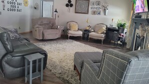 A living room with a sofa, armchairs, a coffee table, a fireplace, and a TV. - Beautiful house located 5 minutes drive to EAA AIRVENTUE (Oshkosh)