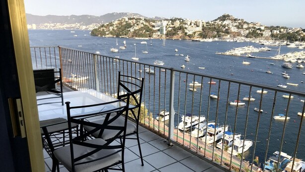Ein Balkon mit Tisch und Stühlen mit Blick auf einen Jachthafen und zahlreiche Boote.