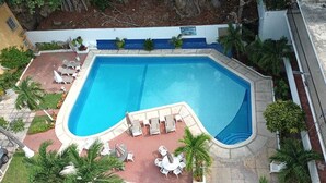 Ein Schwimmbecken mit Liegestühlen und Palmen.