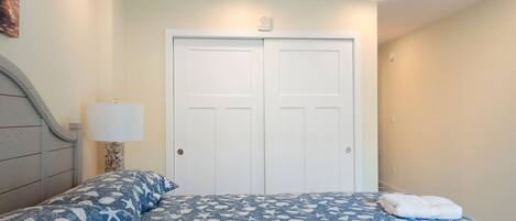 Camera da letto con un letto, due porte, una lampada e una griglia di ventilazione al soffitto.