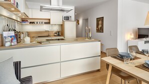 Una cuina moderna amb una illa central, armaris blancs i un microones.