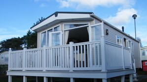 Ein weißer Wohnwagen mit Balkon und überdachter Veranda.
