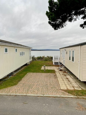 A row of mobile homes with a paved walkway and a grassy area in front.
