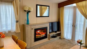 Ein modernes Wohnzimmer mit Kamin, Flachbildfernseher und Essbereich mit Tisch und Stühlen.