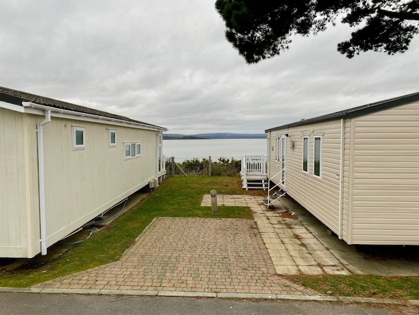 A caravan park with two caravans, a paved walkway, and a view of the sea.