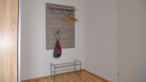A room with a wooden floor, a metal drying rack, a wooden hanger, and a grey wall-mounted rack. - Grimming Lodge Goldrute (Tauplitz)