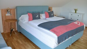 A neatly made bed with a blue headboard, white bedding, and decorative pillows with heart and deer designs. - Grimming Lodge Goldrute (Tauplitz)